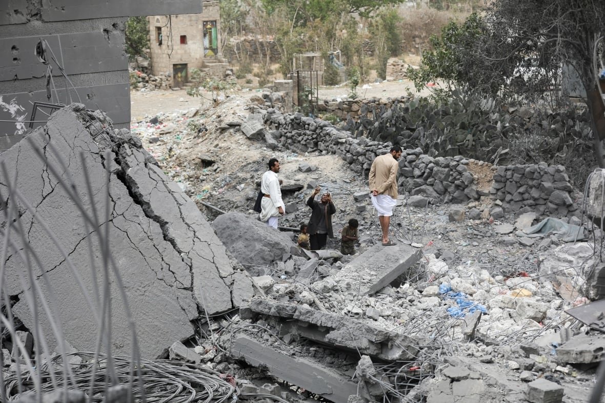 usa-trump-yemen-strike Large amounts of concrete debris are shown, with people shown at a great distance walking among the debris.