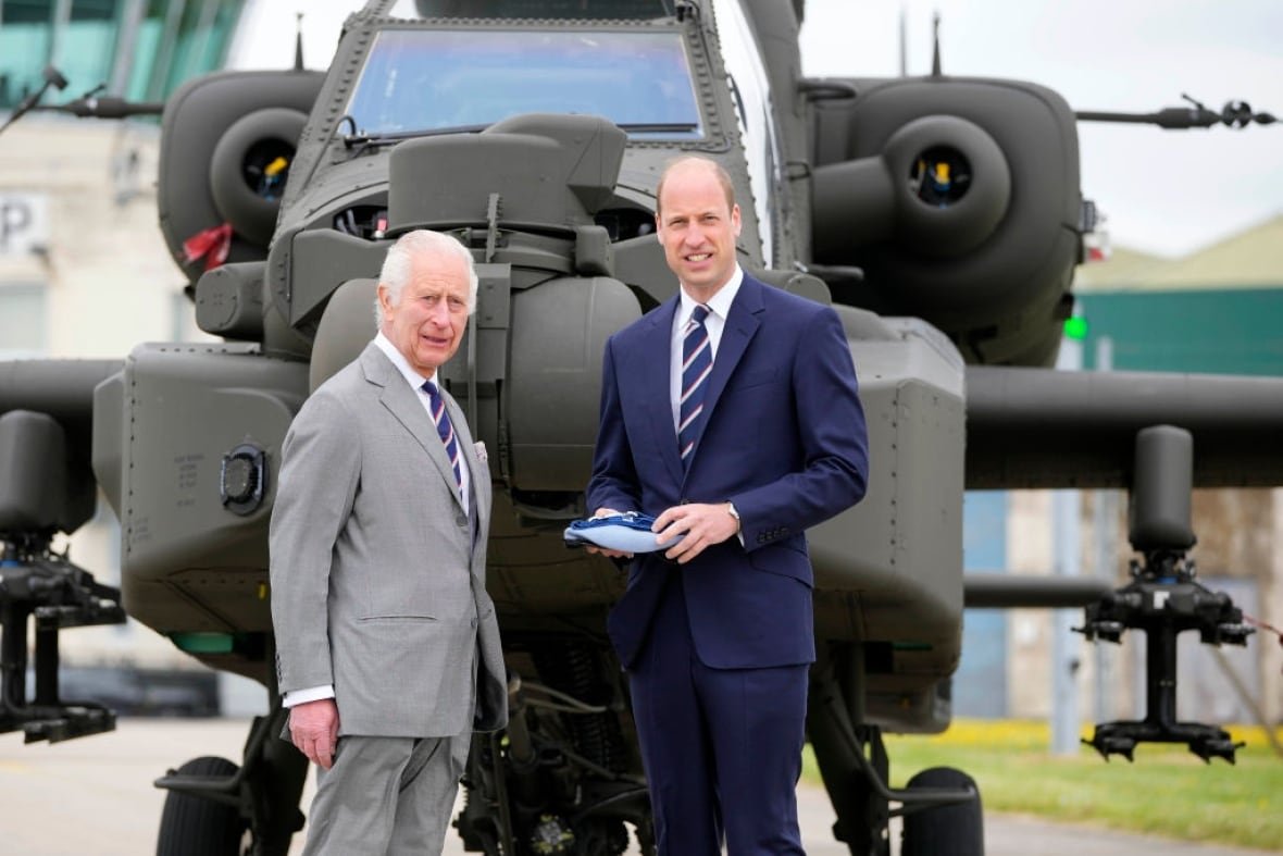 2152208343 Two people stand in front of a military helicopter.