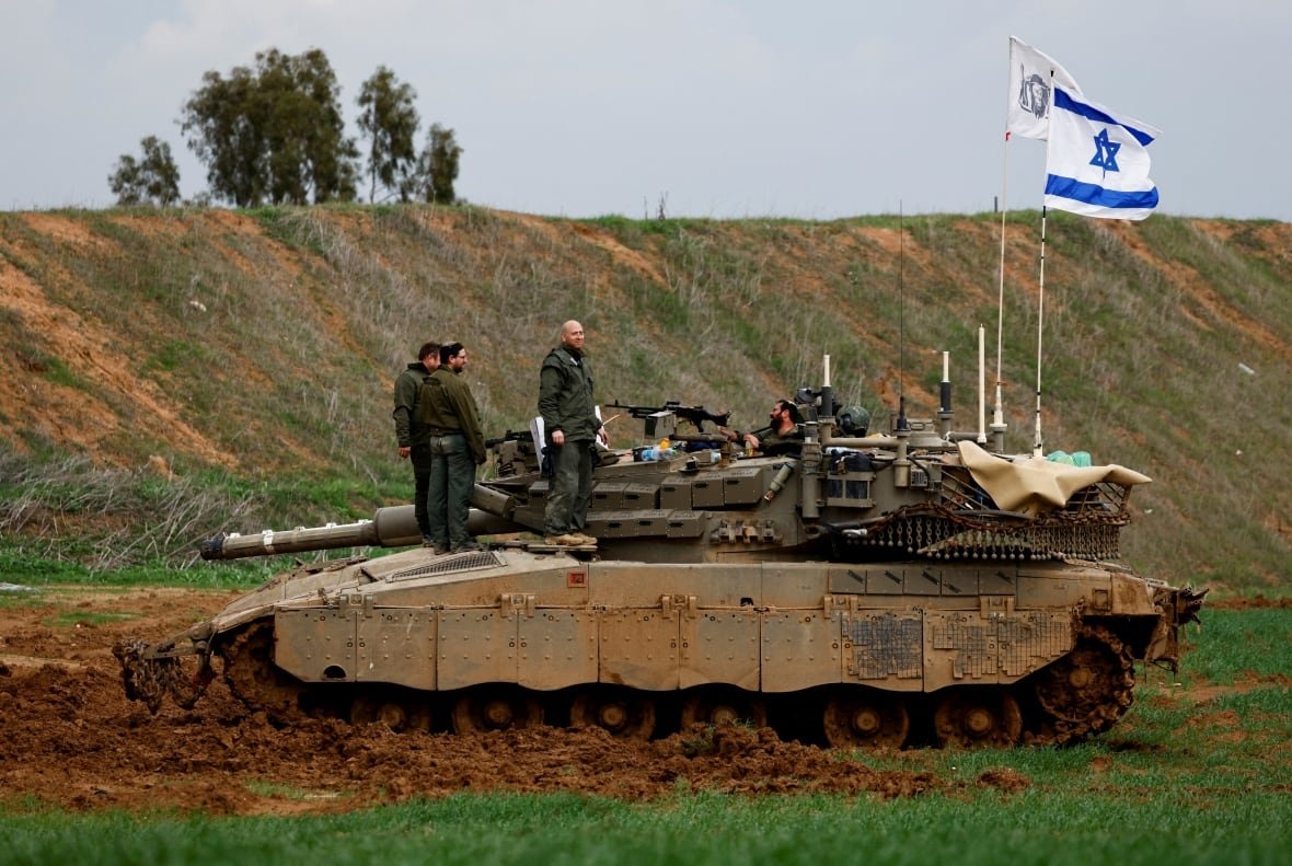 an-israeli-tank-stands-at-the-border-with-gaza Soldiers stand on a tank