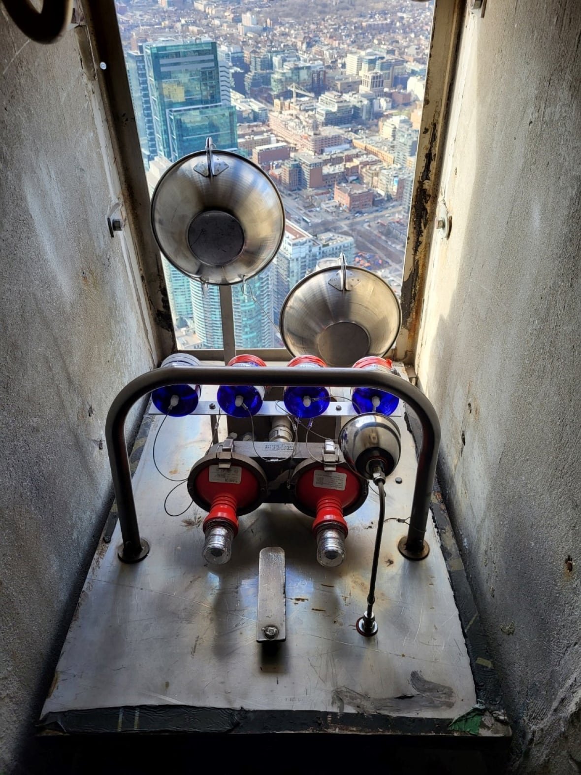 An air quality measuring machine mounted on the CN Tower, looking out on the city skyline.