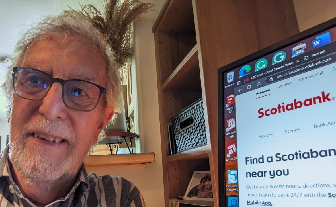 A man poses next to his computer showing the Scotiabank website.