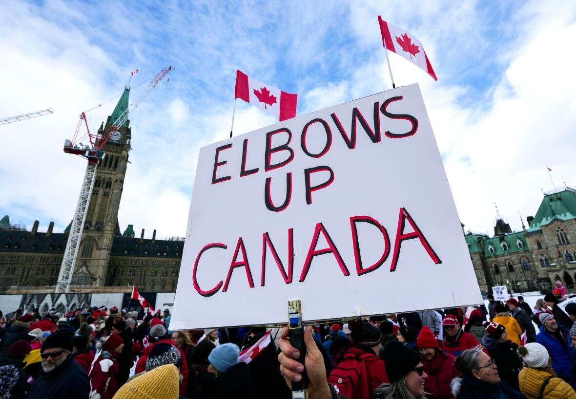A protester holds up a sign that reads, 'Elbows up Canada,' during a rally.