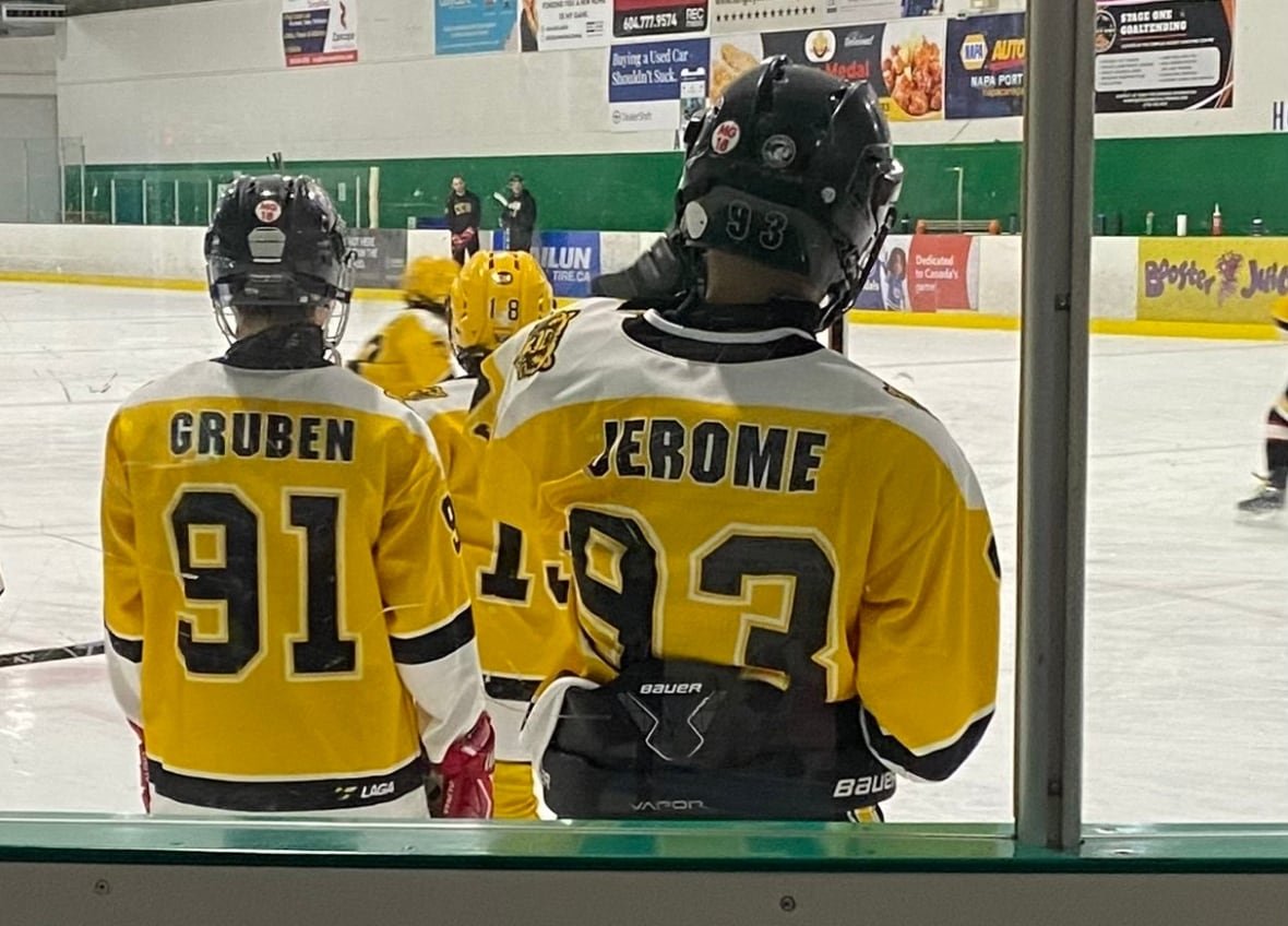 Two kids in hockey equipment on the ice with their names on their jerseys.