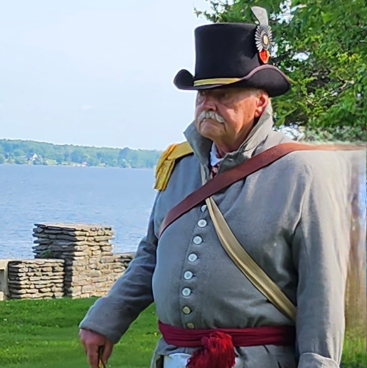 A man stands in an old grey military uniform.