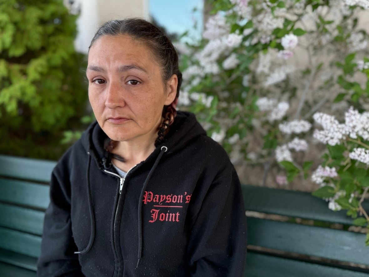 pauline-nabess A woman in a black hoodie looks on with a serious face.
