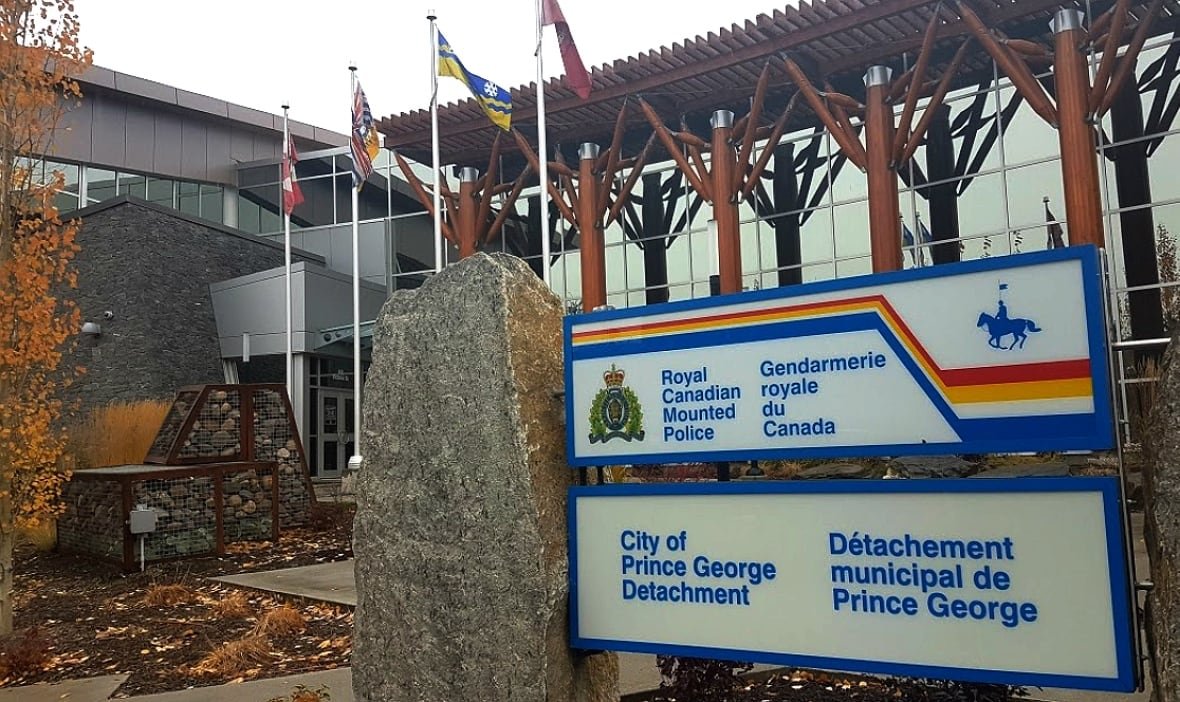 prince-george-rcmp A sign announcing the City of Prince George RCMP detachment is seen next to a stone pillar outside a glass-walled building with trees showing their fall colours.