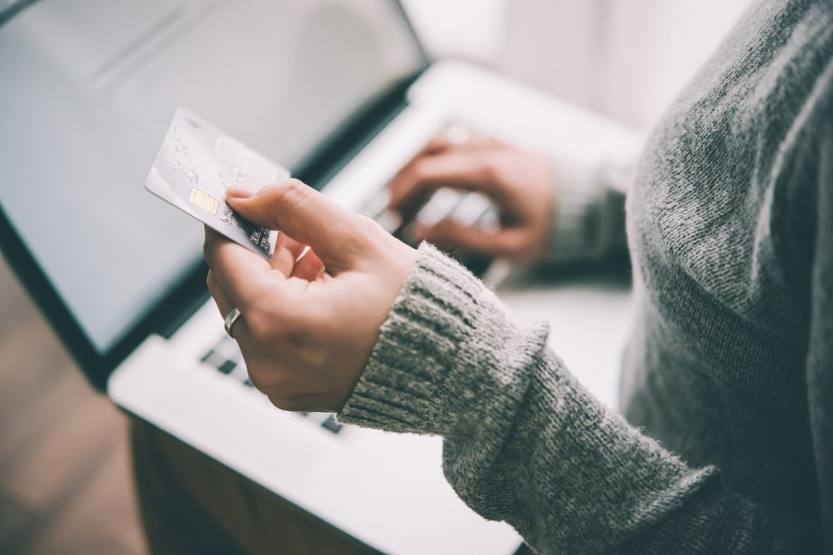 Person typing on laptop while holding a credit card.