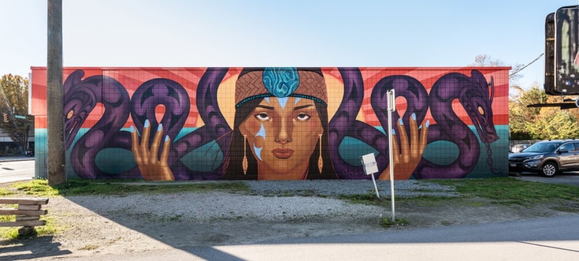 sinulhka-story-of-the-double-headed-serpent A photo of a mural with a woman holding her hands up with two serpents on either side of her.