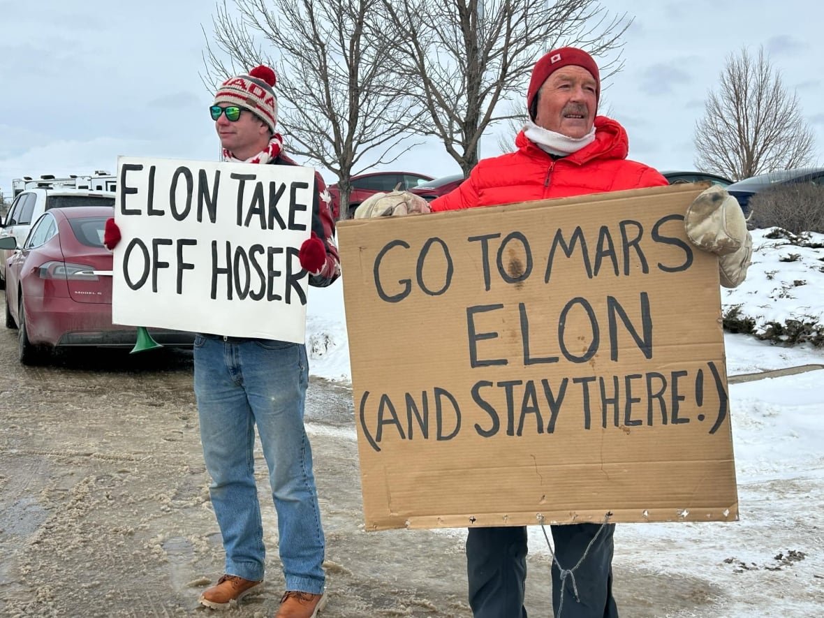 tesla-protest-saskatoon Protesters hold up signs that read, 'Elon take off hoser,' and 'Go to Mars Elon (and stay there).'