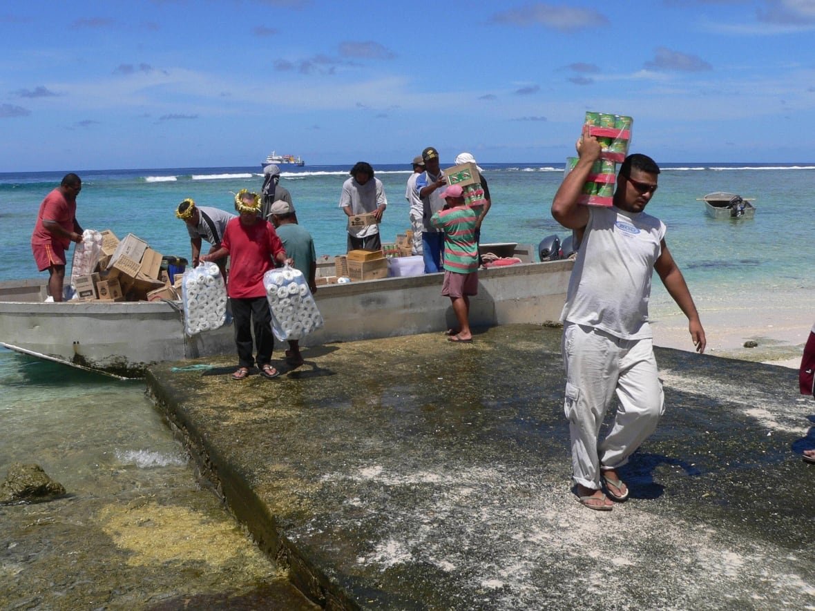 People unload a  small boat on a beach