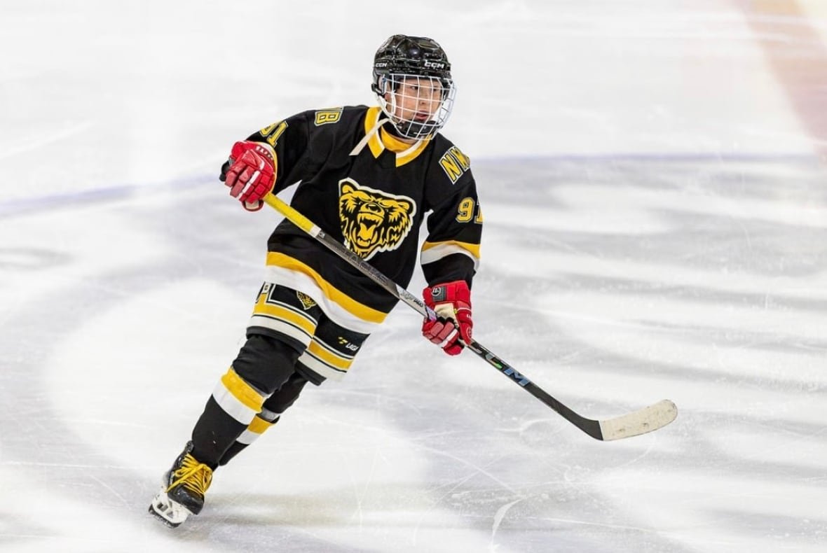 A kid skating on the ice in hockey gear.