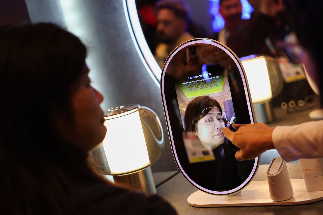 A person interacting with an oval screen resembling a mirror.