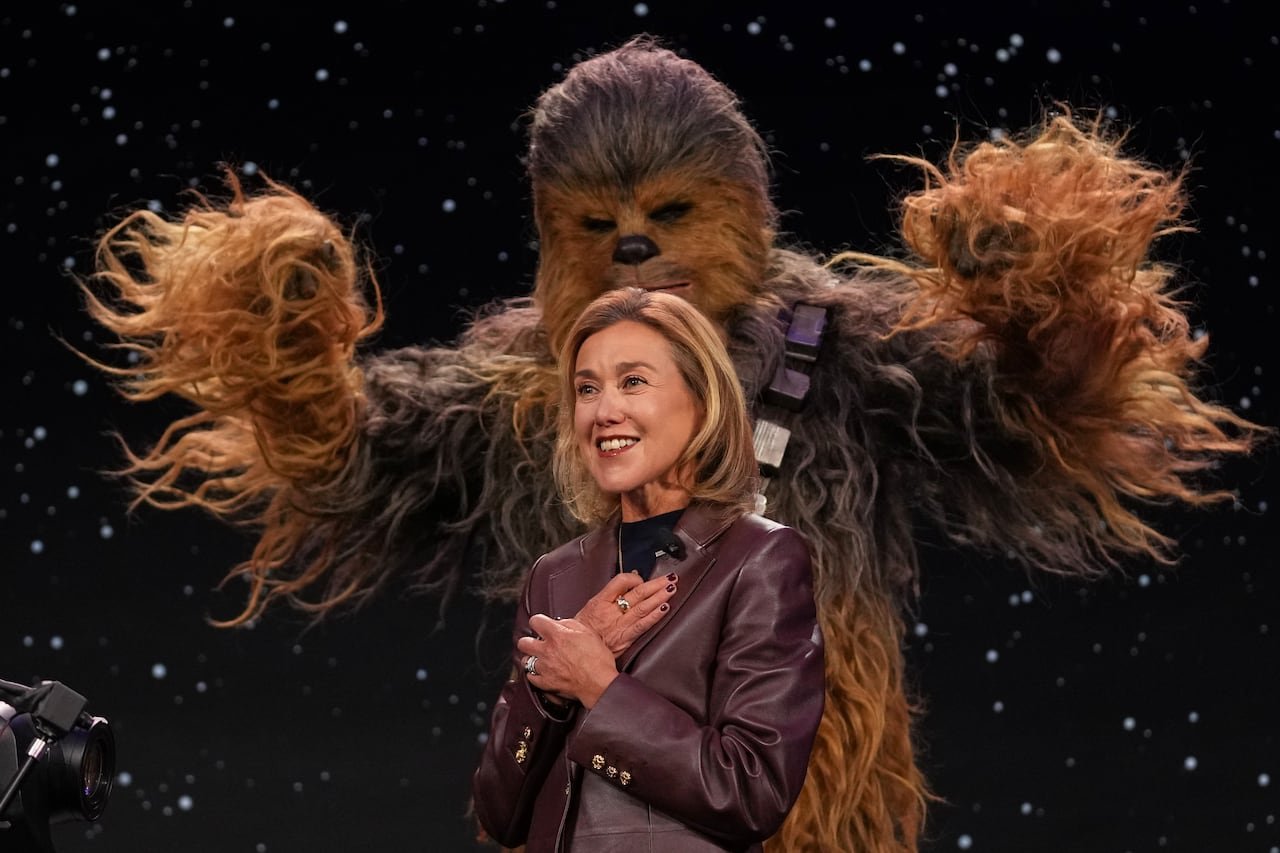 A woman on stage with a person in a Chewbacca costume.