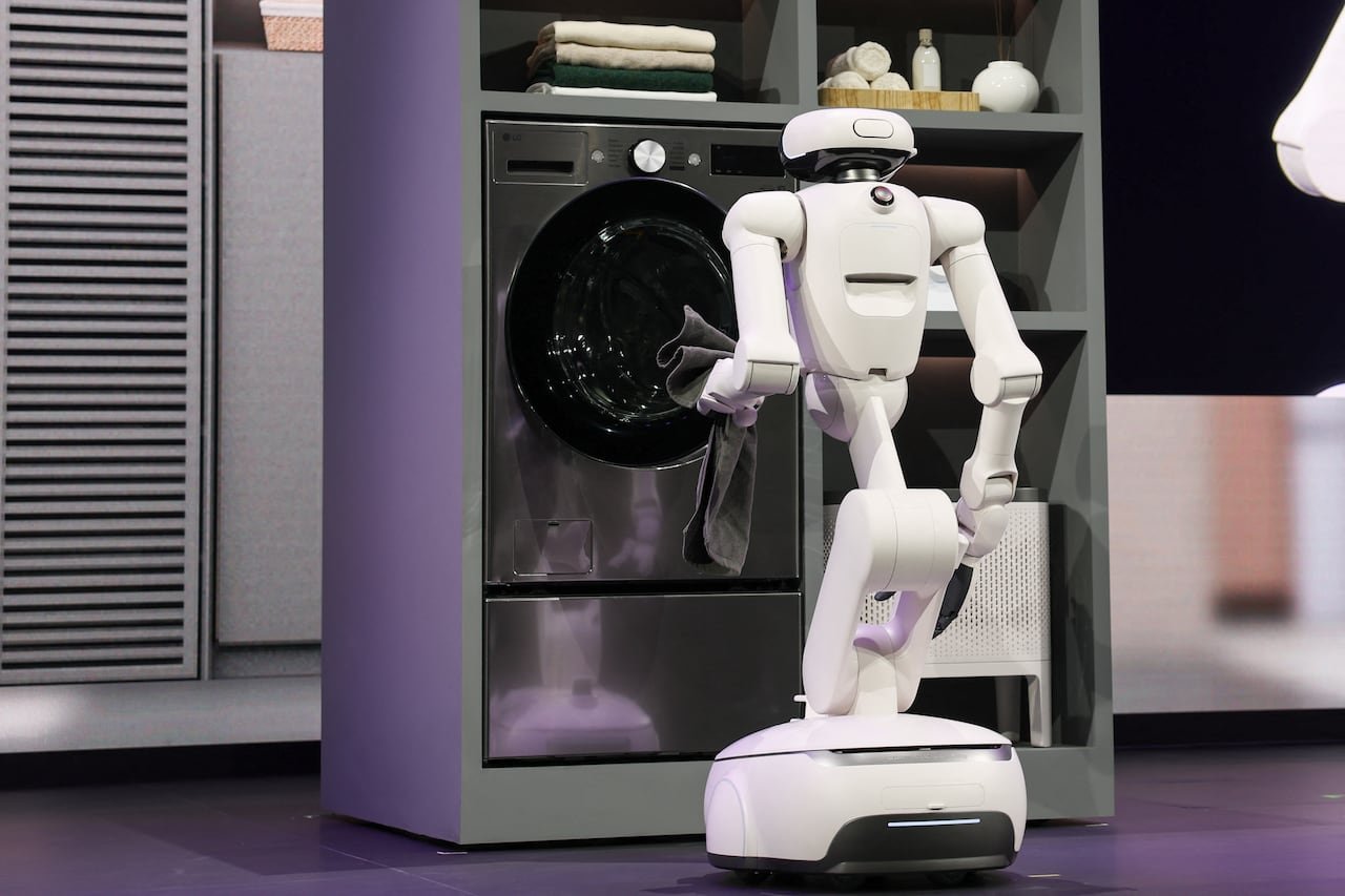 A white robot loading laundry on stage.