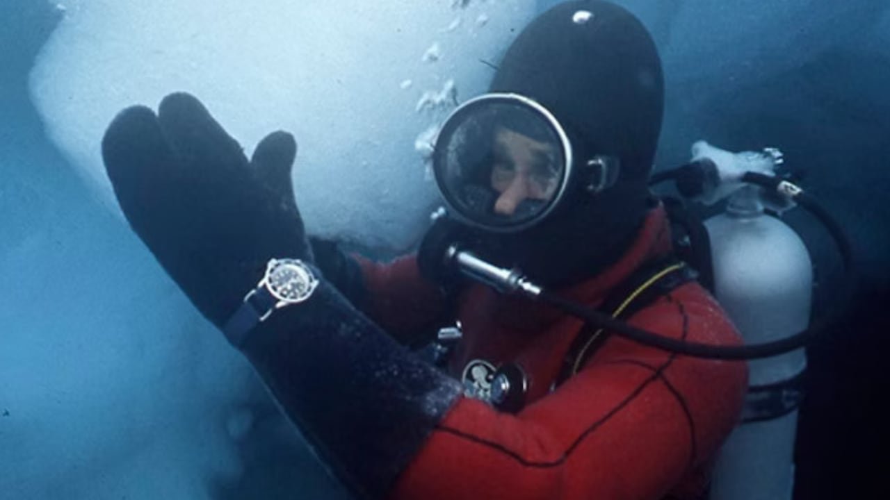 default-333 A man in a thick diving suit grasping a piece of ice in the ocean.