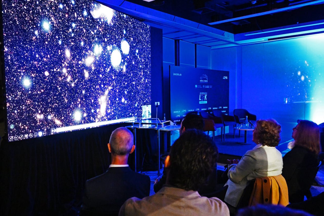 individuals in a meeting room observing outer space images