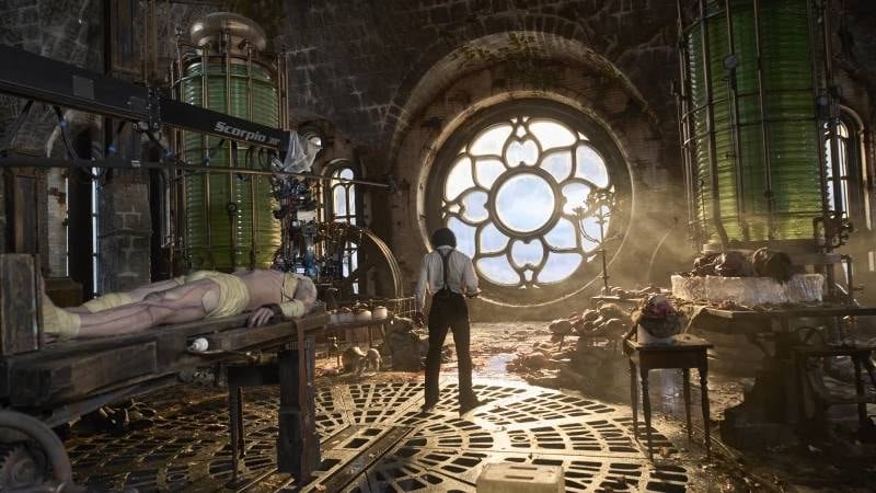 default-204 Interior shot of a fantastical laboratory in a steampunk style. A man stands in front of an enormous circular window, his back to the viewer. Behind him is all manner of old-fashioned lab equipment, very ornate in its making. Cadavers and human body parts lie on various tables and slabs.