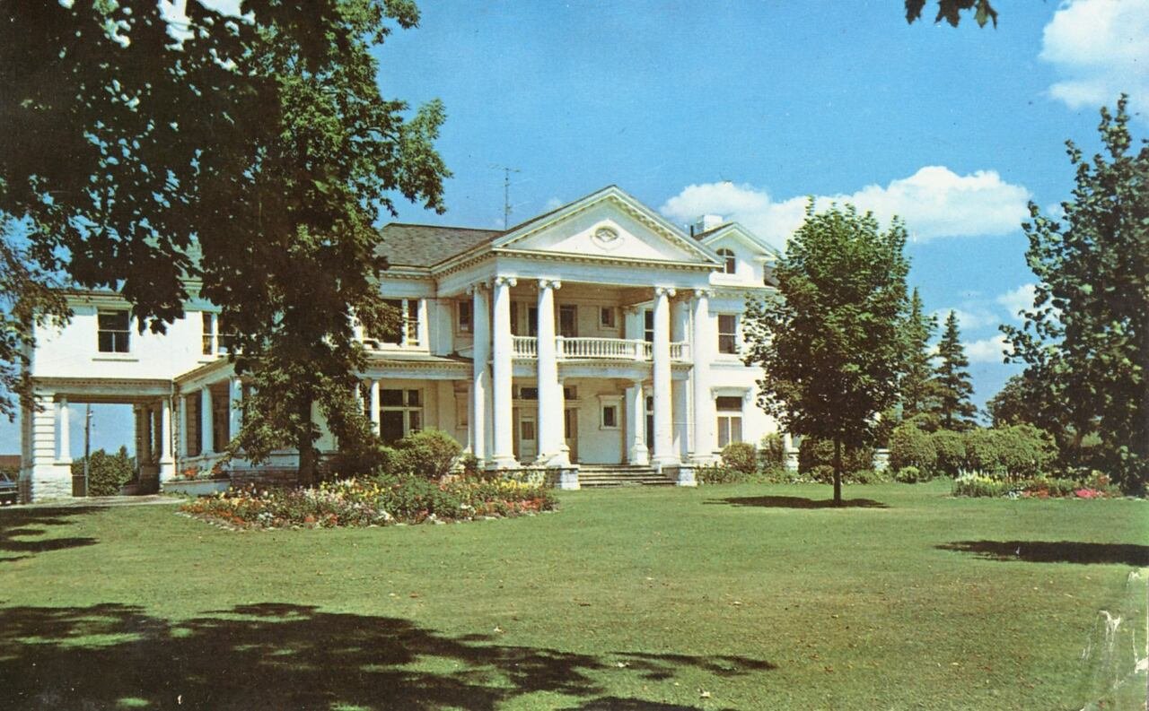 A white building is seen through the trees