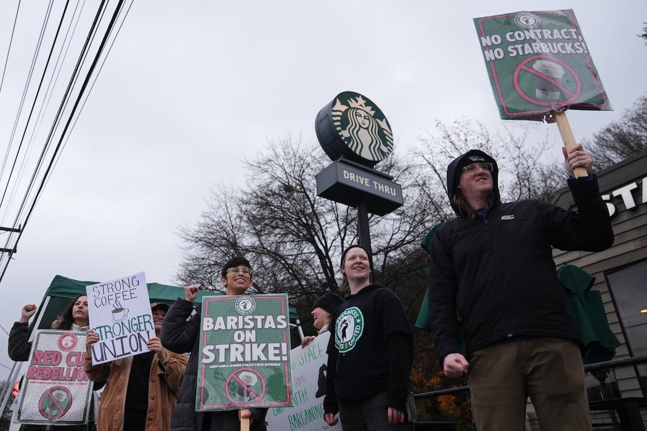 Workers hold picket signs outside of a Starbucks store.