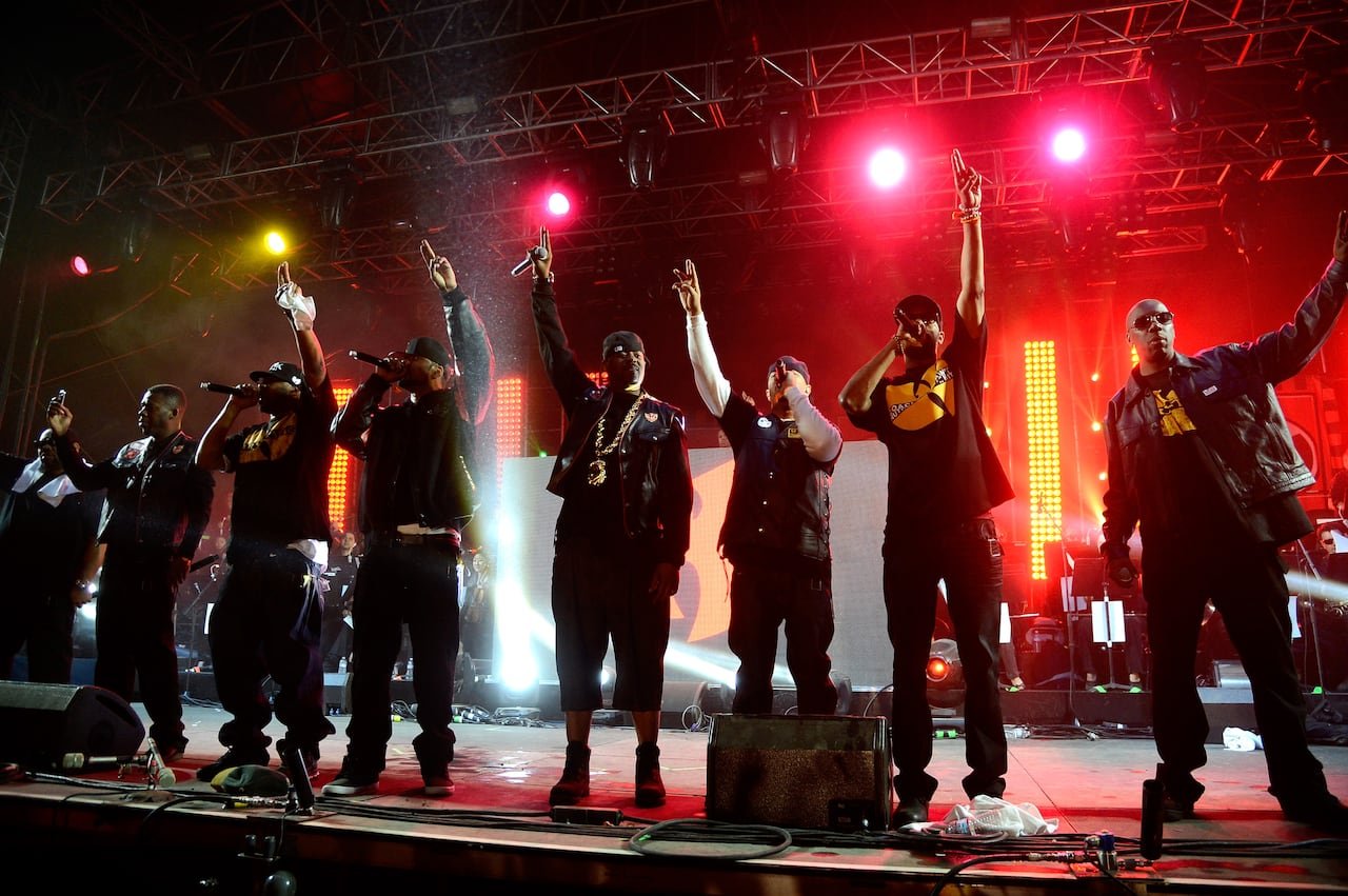 Wu-Tang Clan performs onstage during day 3 of the 2013 Coachella Valley Music & Arts Festival wearing all black with red and orange lights in backdrop on stage