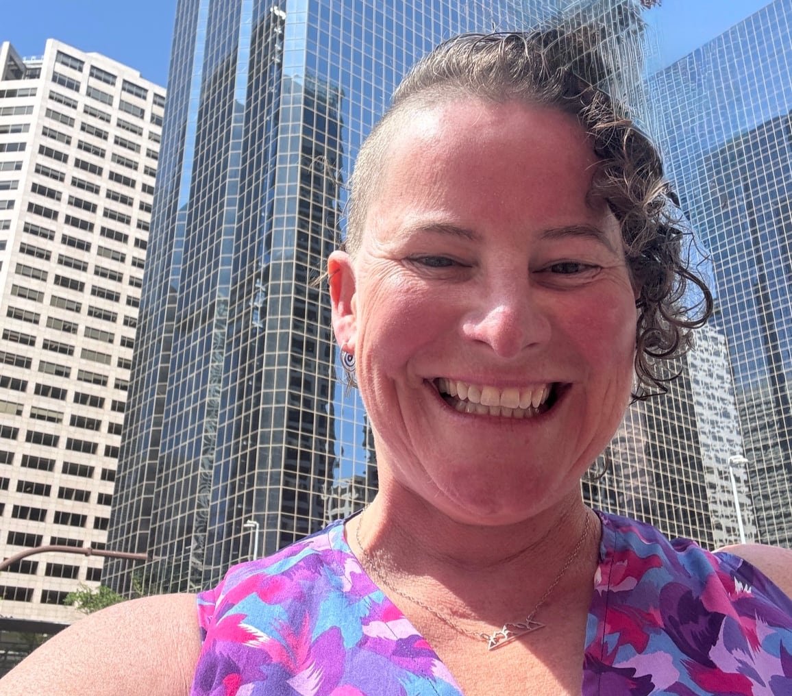 default-355 A woman smiling with tall office buildings in the background.