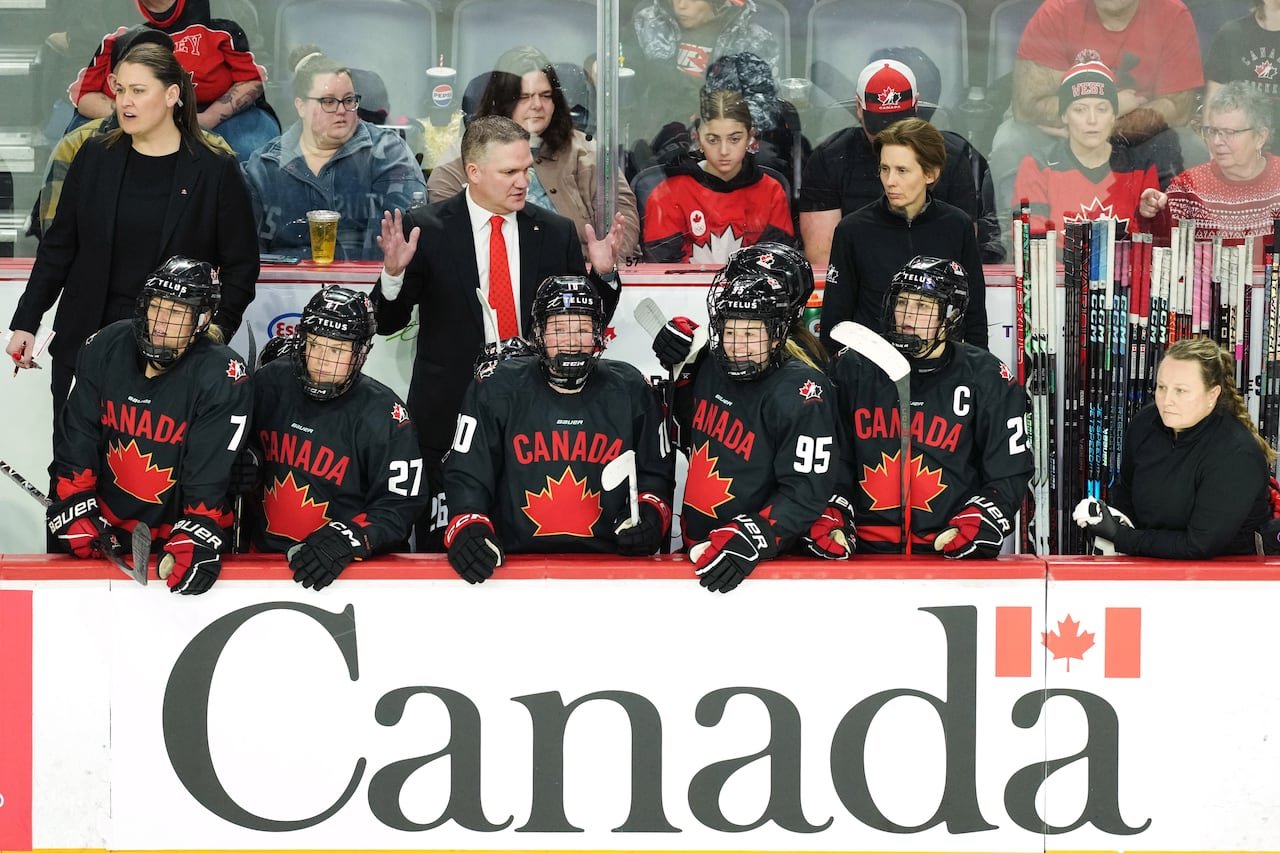 default-74 Players and coaches are shown on the bench during a hockey game.
