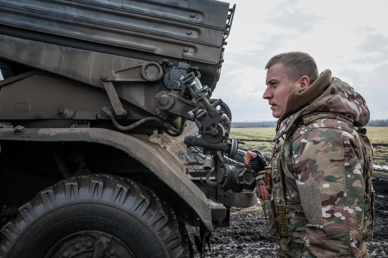 default-194 A soldier stands in a field next to a vehicle rocket launch system.