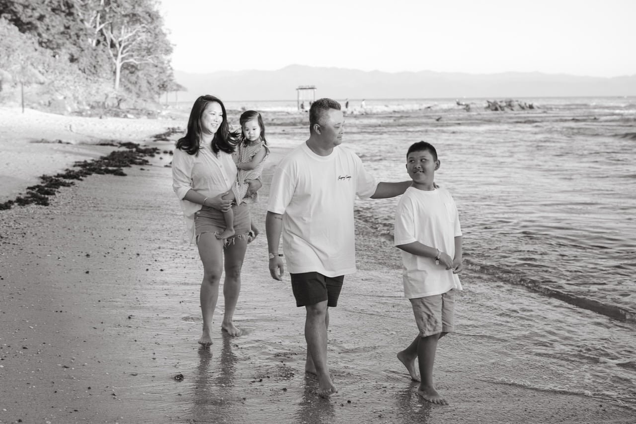 A black and white photo of a family of four on the beach.